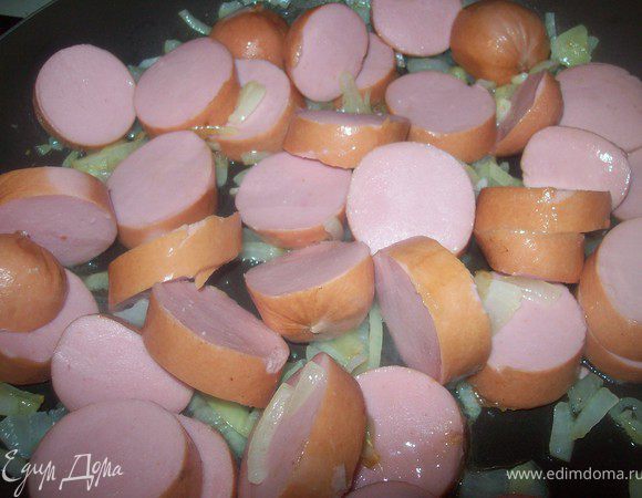 Добавить сардельки к луку, перемешать и жарить 5 минут