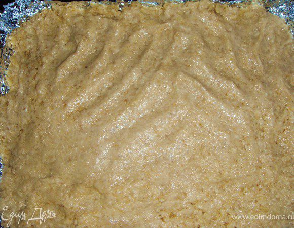 Выложить тесто в проложенную бумагой для выпечки форму, разровнять влажными руками.
