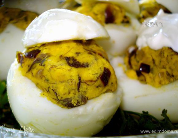 Яйца (белки) аккуратно ложечкой наполнить получившимся фаршем. В салатник выложить зелень, затем на нее яйца, прикрыв «крышечками». 