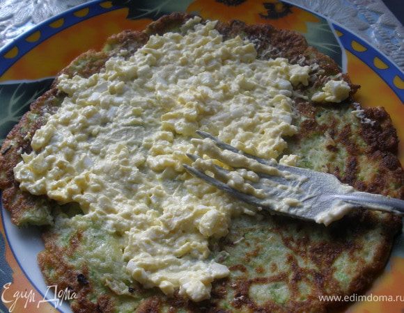 Приготовить начинку.
Сырки, сваренные в крутую яйца натереть на мелкой терке, добавить чеснок через чеснокодавку и майонез. Все тщательно перемешать и смазать этой смесью оладьи.