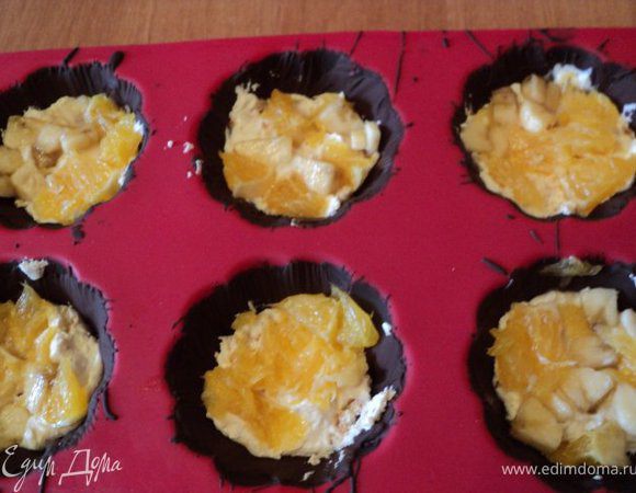 Формочки с застывшим шоколадом наполнить на 1/3 творожной массой, сверху уложить  немного порезанных фруктов.