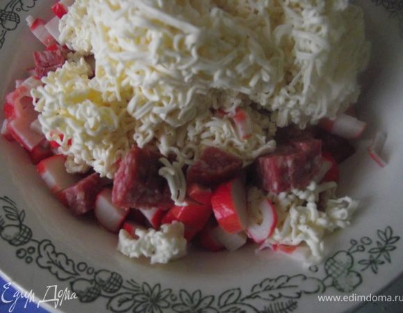 Порезать кубиками колбасу и крабовые палочки. Натереть сыр и чеснок на мелкой терке. Заправить майонезом и украсить зеленью. Приятного аппетита!!!