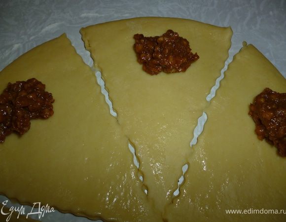 9.Берем шар теста и скалкой раскатываем круглую лепешку толщиной 0,5см,разрезаем на треугольники.На широкую сторону кладем начинку и скатываем рулетик,придаем ему форму полумесяца.Выкладываем изделия на противень,выстланный бумагой смазанной растительным маслом.Даем им расстояться 15-20минут,смазываем взбитым желтком и выпекаем в духовке при 170-180градусах до приятного румяного цвета.Готовые круассаны достаем из духовки,накрываем полотенцем и даем постоять 10-15 минут.А затем наливаем чай или молоко и наслаждаемся вкусной и ароматной выпечкой.Приятного вам чаепития:) 