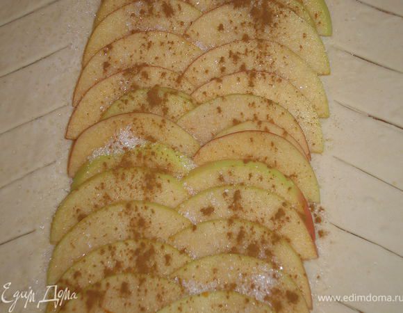 Центральную часть теста посыпать сахаром.
Выложить дольки яблок, посыпать сахаром и корицей.
