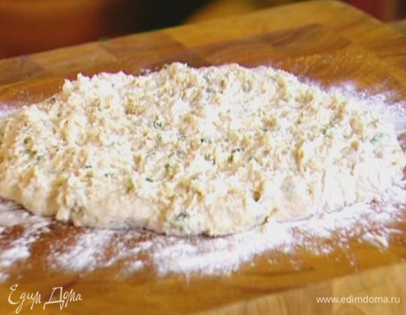 Рабочую поверхность присыпать мукой, выложить тесто и сформировать пласт толщиной 2 см, слегка присыпать сверху мукой и оставшимся твердым сыром.