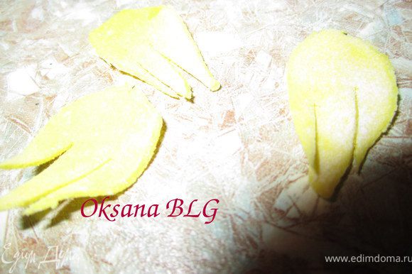 Из желтой мастики вырезать маленькие листики, на них сделать 2-3 разреза.