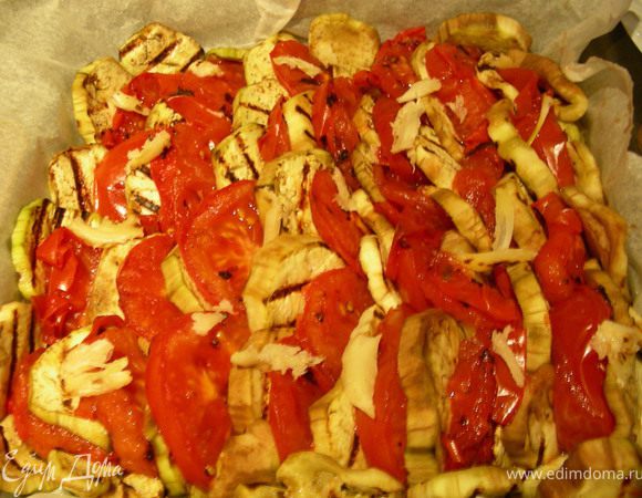 Теперь разогреваем нашу духовку, в рецепте до 240 гр (по-моему, это перебор), у меня духовка-зверь, да еще и с конвектором, потому я обошлась 200 гр. Форму для запекания немного смазываем маслом (я ее застелила бумагой для выпечки) и выкладываем баклажаны и помидоры по очереди в нахлест. Сверху раскрашиваем чеснок. 
