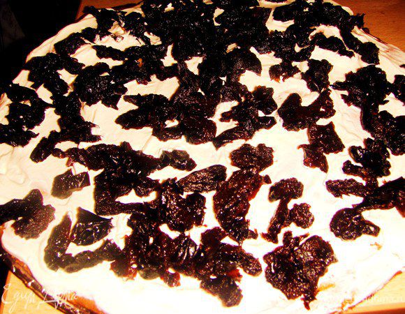 На тарелку выложить корж, сверху  1/4 крема, разровнять его. Сверху выложить половину количества чернослива.
