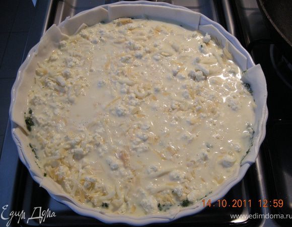 На тесто выложить остывший шпинат, сверху засыпать сыром и всё залить яично-молочной смесью . 