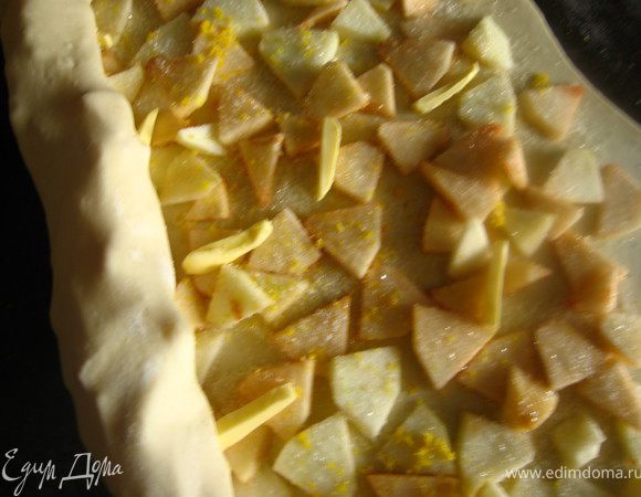  выкладываем начинку 2: т.е яблоки раскладываем равномерно по всей поверхности, отступая от края 1см. на яблоки, цедру лимона ( трем на мелкой терке), сахар и кусочки размягченного сливочного масла (20гр). Количество сахара регулируйте сами, в зависимости от кислоты яблок. У меня ушло грамм 50.Сворачиваем в рулет. Укладываем на противень застеленный фольгой. Можно обойтись без нее, но в посудомойку противень не влезает, а мыть руками лень.