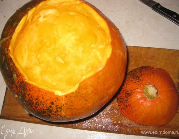 Для начала с нашей тыквы срезаем верх и с помощью ножа и ложки вынимаем всю середину, включая семечки и мякоть. Оставляем толщину стенок приблизительно 1 см.
