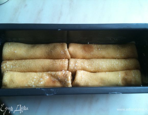 Каждый блин смазать творожной начинкой и свернуть рулетиком. Выложить плотно на дно формы.