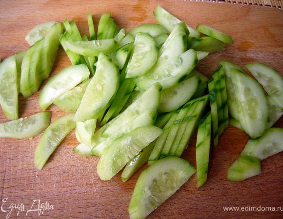 Огурец разрезать вдоль пополам, затем дольками наискось поперёк. 