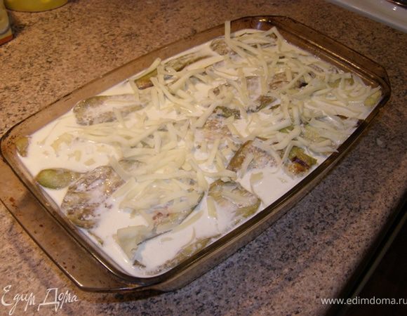 Молоко, тем временем, уварилось до половины объема))) Помешивая, засыпаем в молоко тертый сыр. Полученной смесью заливаем баклажанницу, сверху посыпаем тертым сыром