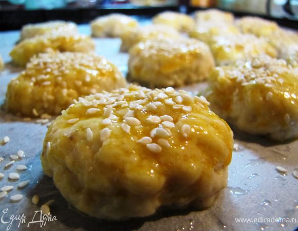 Включаем духовку, пусть нагревается. В это время замешиваем тесто. Для этого Все ингредиенты вместе помещаем в миску, перемешиваем пару-тройку минут. Из полученного теста формируем лепешки-шарики, которые выкладываем на промасленный пергаметр, смазываем взбитым желтком и густо посыпаем кунжутом.