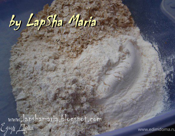 Добавляем просеянную муку с солью, измельченные в крошку хлопья, обычные хлопья и разрыхлитель. Хорошенько вымешиваем.