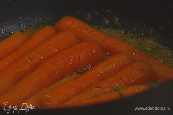 Разогреть в тяжелой глубокой сковороде сливочное масло, выложить морковь, добавить листья тимьяна, мед, оставшиеся семена кориандра и молотый имбирь. Все перемешать и обжаривать пару минут.