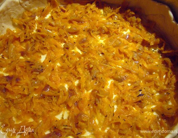 Тесто делим на 2 части, одна должна быть примерно на треть меньше. Большую часть раскатываем в круг большего диаметра, чем Ваша форма для запекания или сковорода. Я брала разъёмную форму диаметром 24 см. Дно застелила пергаментом, а бока смазала топлёным маслом. 
Выкладываем тесто в форму, делаем бортики почти на всю высоту, прижимаем их хорошо к стенкам. Тесто смазываем топленым маслом при помощи кисточки. Выкладываем первый слой начинки, это лук с морковью. Стараемся "отжать" слегка овощи, лишний сок нам не нужен.