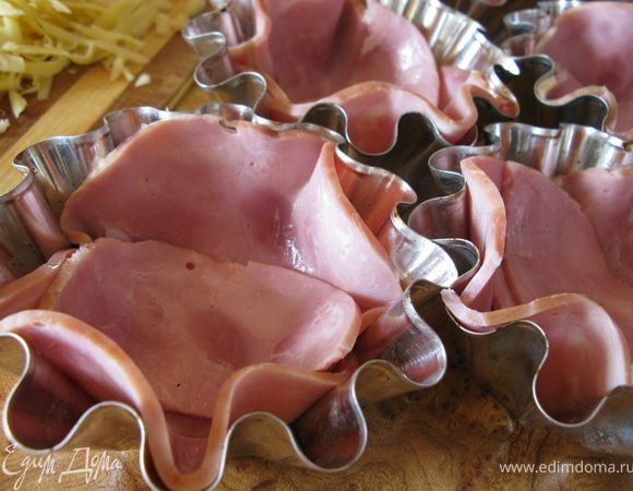 Маленькие формочки смазать маслом и выложить дно и стенки тонкими ломтиками ветчины.