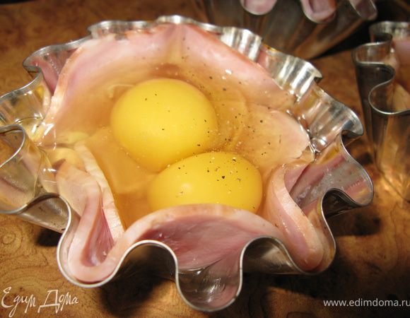 В каждую формочку на ветчину выпустить по 2 яйца. Солим, перчим.