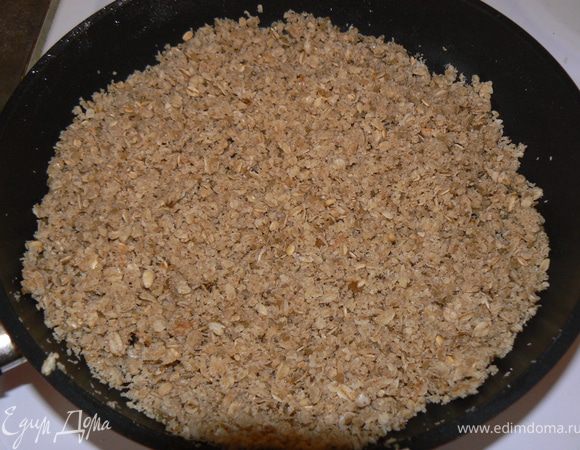 приступаем к коржу - на сковороду высыпать овсяные хлопья, сахар, масло и на среднем огне нагреть, помешивая лопаткой. Как только сахар начинает плавиться, снять с плиты и отставить охлаждаться. Дно разъёмной формы, диаметром 26 см выстилить бумагой для выпечки.