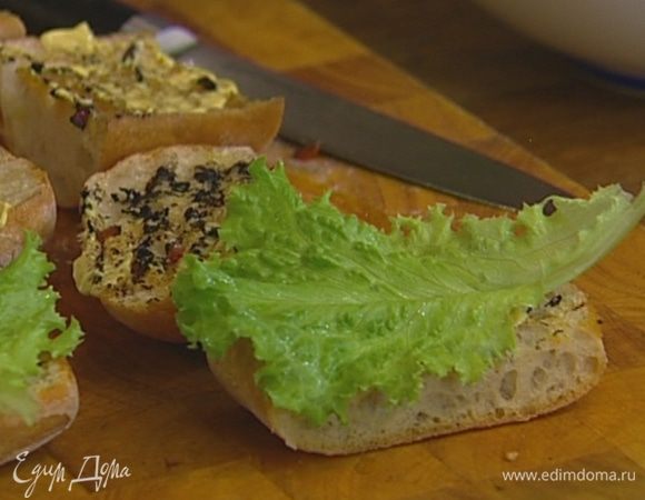 Листья салата вымыть, высушить и разложить на 4 половинки хлеба.