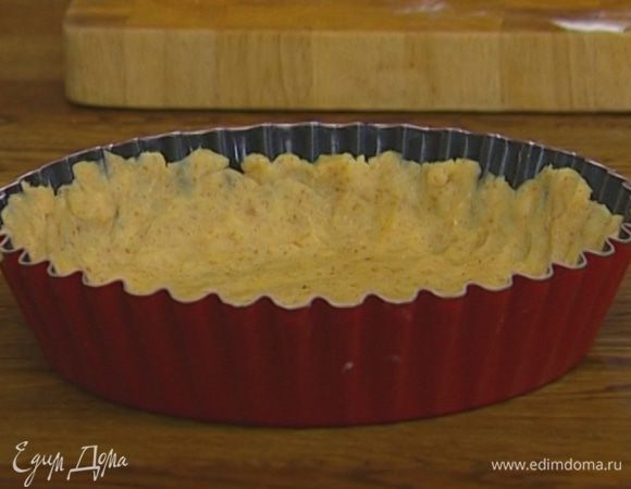 Рабочую поверхность присыпать мукой, раскатать тесто в пласт и переложить в форму для выпечки, равномерно распределив его по дну и бортикам.