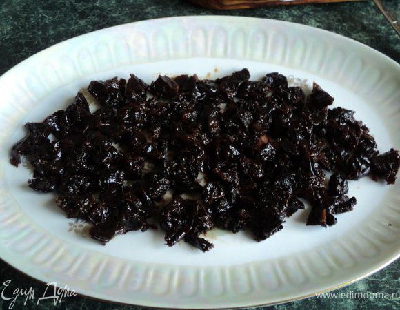 Чернослив залейте на 15 минут горячей водой, затем слейте воду и нарежьте чернослив кусочками. Выложите на дно продолговатого блюда.