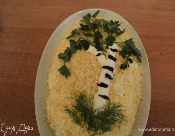 Верхний слой — мелко натертый сыр. Украшение: ствол березки из майонеза, полосочки на коре — из чернослива, укроп и петрушка. 