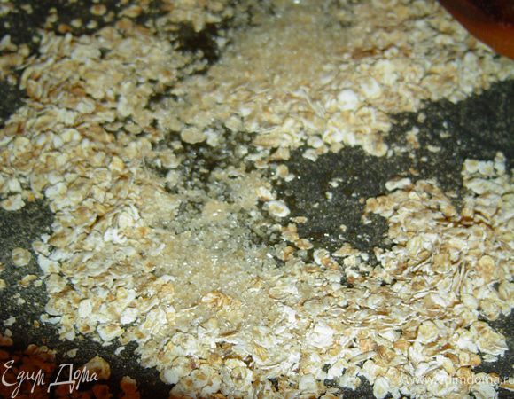 Овсяные хлопья высыпаем на сухую сковороду, поджариваем на медленном огне, постоянно помешивая, пару минуты, до изменения цвета, а затем добавляем коричневый сахар и перемешиваем.