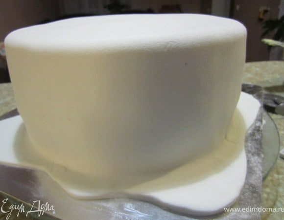 Достать из холодильника, покрыть масляным кремом, выровнять. Покрыть белой мастикой, край фигурно вырезать.