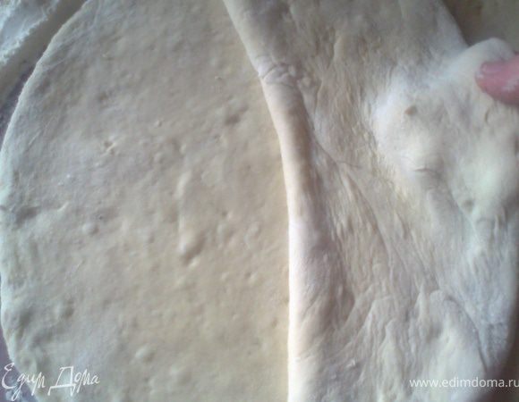 Разделить тесто на две части,раскатать каждую,уложить друг на друга и снова раскатать поверху.Лучше это делать на пергаменте,чтобы без хлопот перенести на противень.