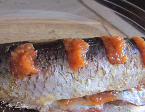Запекаем рыбу при 200 С в режиме конвекции минут 40 и при обычном режиме минут 50. Затем достаем рыбу и в надрезы к чесноку добавляем аджику. Также аджику кладем в брюшко рыбы. Отправляем рыбу в духовку еще минут на 10.