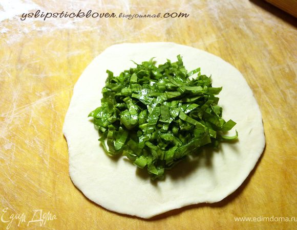 Достать тесто, разделить на части и скатать их в шары величиной с грецкий орех (или чуть больше). Раскатать шар в круг толщиной 3 мм, в середину щедро выложить щавельную начинку и завернуть края.