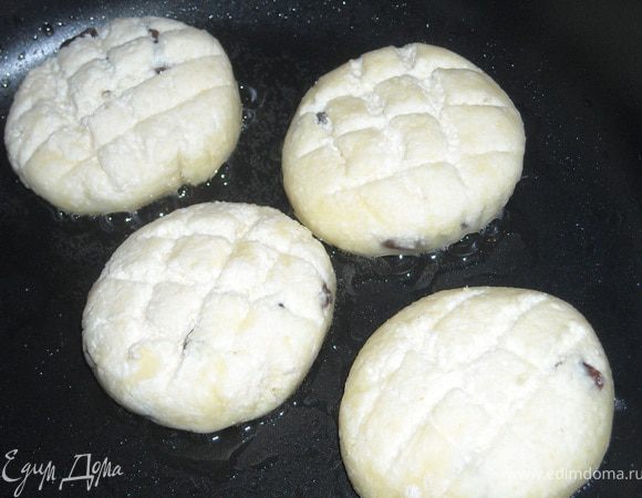 Мокрыми руками сформируйте шарик из творожной массы (примерно 1 ст. л.), хорошо обваляйте его в муке, слегка приплюсните и жарьте на сковороде с толстым дном на медленном огне под крышкой с небольшим количеством масла.