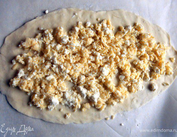Покрыть тонким слоем сыра, оставляя свободным края теста.