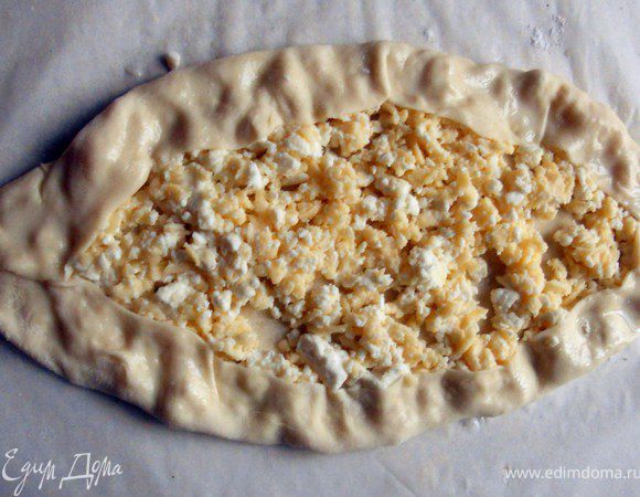 Сформировать "лодочку", часть сыра накрыв тестом. Взбить желток (можно добавить немного молока) и кисточкой смазать тесто. 