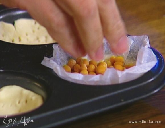 Вырезать из бумаги для выпечки круги, большие по объему, чем формы для кексов, вложить их в тарталетки, а сверху насыпать горох или фасоль.