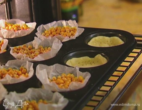 Отправить формы в разогретую духовку на 5 минут, затем удалить горох и выпекать еще 5 минут.