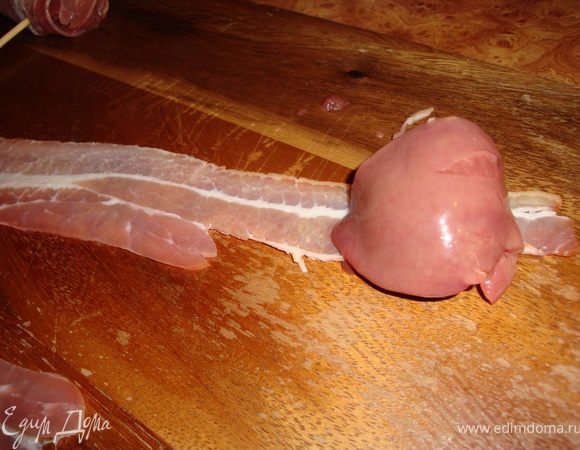 Тоненькую пластиночку бекона раскладываем на рабочей поверхности. На неё кладем кусочек куриной печенки. Я солить не стала, так как бекон оказался солоноват. Вы, если будете готовить, ориентируйтесь сами.