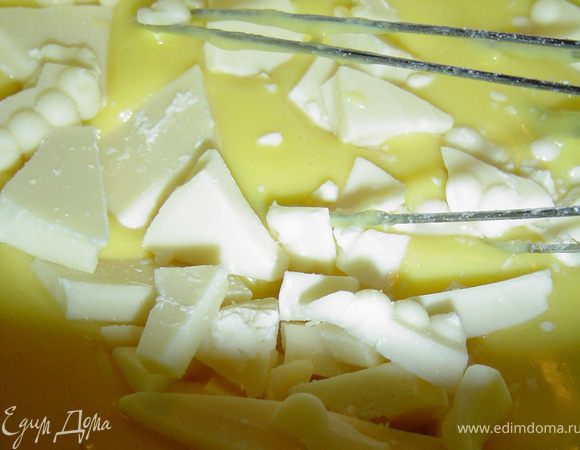 Тонкой струйкой вливаем горячее молоко, при этом непрерывно помешиваем, чтобы не образовывались комки. Варим на слабом огне, пока не загустеет, а затем добавляем ванильный сахар и белый шоколад,