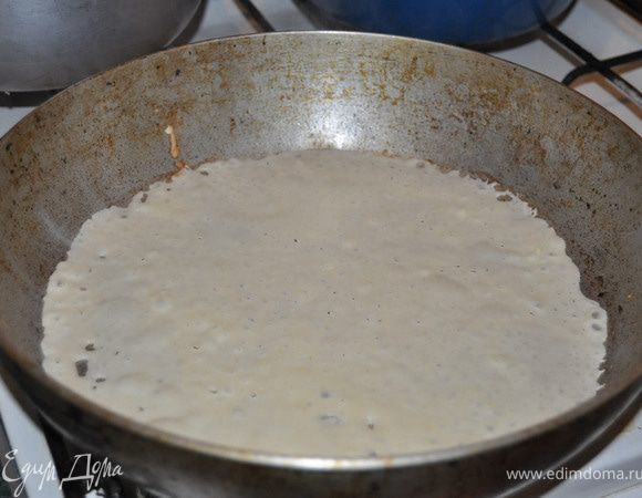 На смазанную сковороду налить небольшой половник теста . Наклонить сковороду в разные стороны, чтобы тесто распределилось по дну.
Поставить сковороду на огонь и печь блин около 1 минуты.
