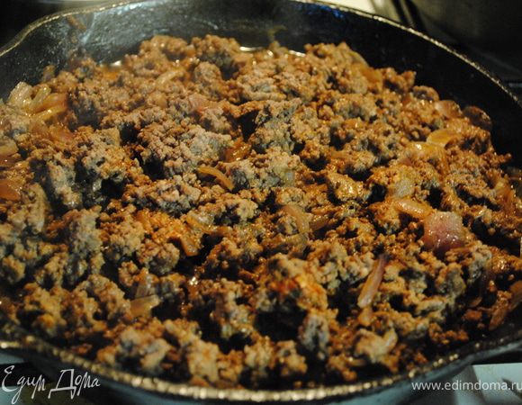 Лук нарезать и обжарить до золотистого цвета. К луку добавить фарш. Обжаривать до тех пор, пока фарш не станет коричневым. Затем добавить томатную пасту, соль, черный перец, базилик и влить вино. Тушить под крышкой 10-15 мин.