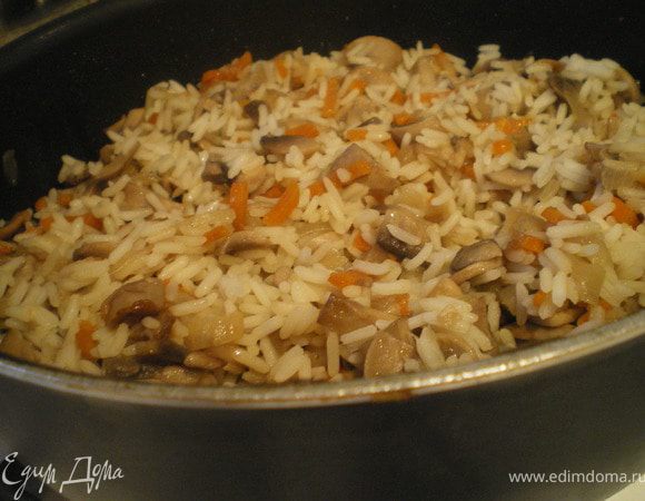 Шампиньоны отварить. Затем обжарить, добавить морковь и мелко нарезанный лук. Посолить. Тушить 15 минут. Засыпать рис, добавить грибной бульон и тушить до готовности риса. 