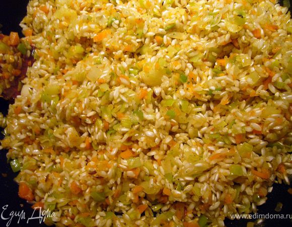 Следующим этапом будет тостатура - обжаривание риса. Круговым движением засыпаем рис в сковороду и перемешаем его с базой из овощей. Будем готовить, помешивая, пока всё масло не впитается в рис. Затем вольём вино, перемешаем и продолжим готовить до исчезновения запаха алкоголя (примерно минут 5) и пока рис не впитает всё вино.