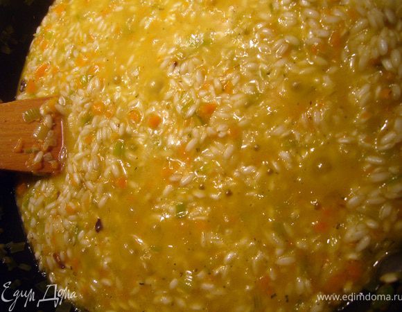 Следующий этап - добавление бульона. Бульон должен быть под рукой горячим, почти кипящим. Вливаем 2 половника бульона, перемешиваем рис деревянной лопаткой непрерывно и аккуратно, круговыми движениями. Как только вся жидкость впитается, добавляем ещё половник, продолжаем помешивать, и так далее, примерно каждую минуту. После второго добавления бульона я добавила ещё приправу Песто с грибами. Сушёные грибы и травы дают изумительный аромат.