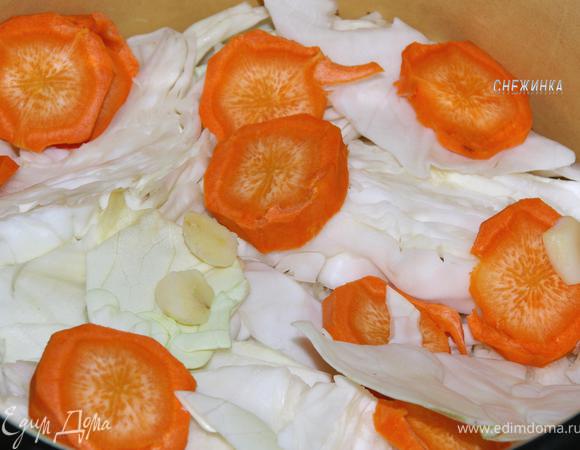 Капусту уложите плотно в кастрюлю, чередуя с морковью и чесноком.