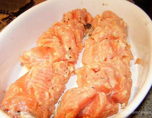 Смажем филе форели чесночной смесью, свернем рулетом, уложим в форму