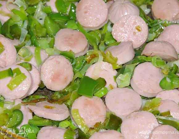 Затем добавляем сосиски и жарим на хорошем огне до их зарумянивания.