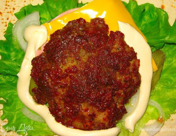 Теперь начинаем готовит наши вкуснейшие бифроллы! Для этого возьмем тонкую лепешку, я брал итальянскую фокаччу, в центр выложим салатные листья, ломтики корнишонов, и кусочек сыра чеддер. Достанем из холодильника наши чудесные бургеры и обжарим их на гриле с двух сторон. Переложим в каждую лепешку наши румяные бургеры поверх зеленого салата и добавим немного соуса, сделанного из натурального йогурта, горчицы и яичного желтка.